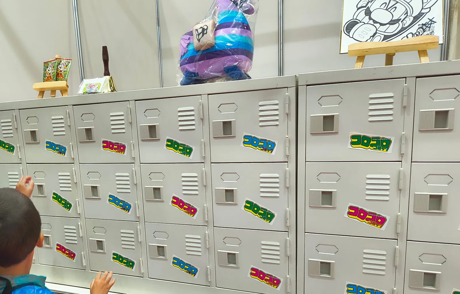 8月29日のコロフェスで、コロコロのシールが貼られたロッカーくじの扉に手を伸ばす後ろ姿