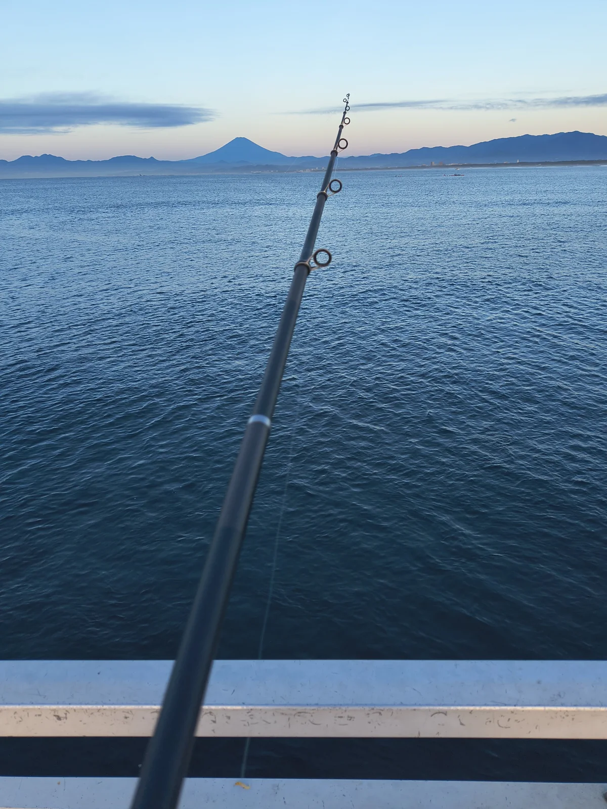 海に向けた釣り竿と、向こうに見える富士山